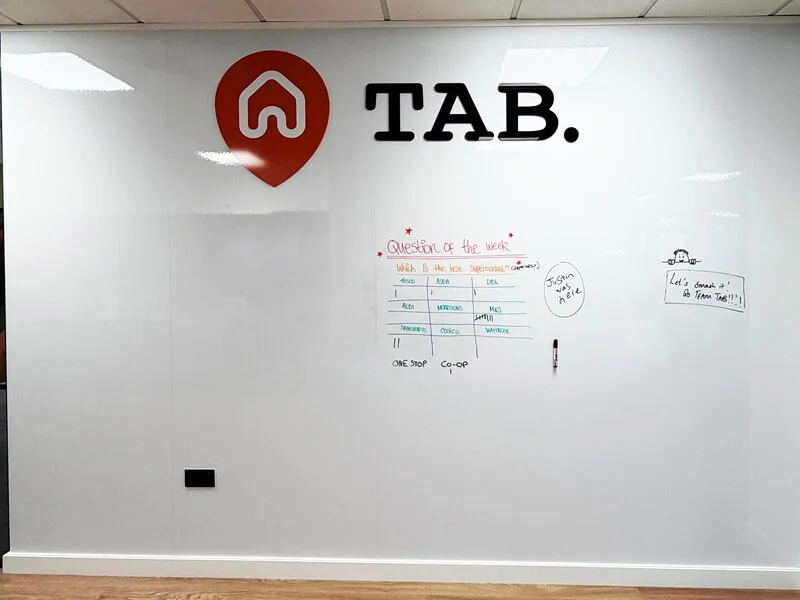 Branded whiteboard featuring precision-cut vinyl TAB logo graphics created by FASTSIGNS St Albans.